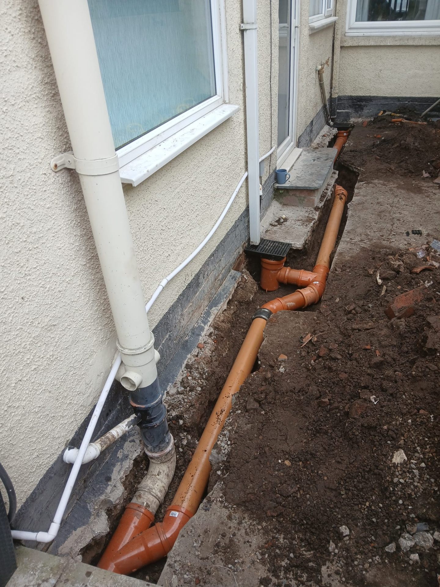 New underground drain pipe installation along side of property with fresh excavation