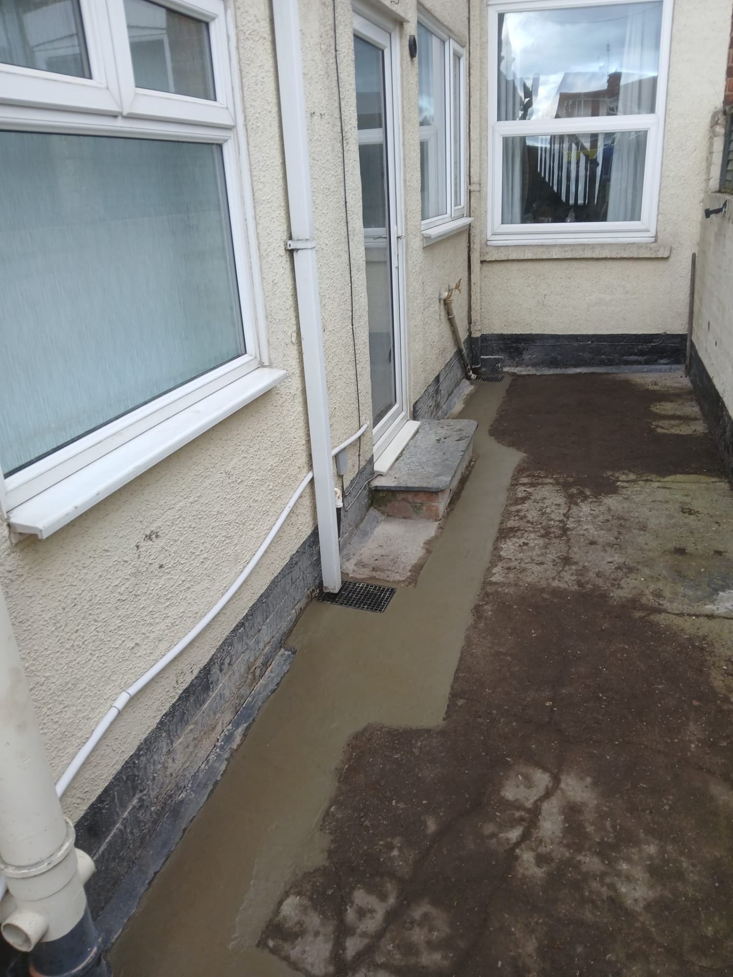 Side passage with freshly laid concrete and new drainage channel