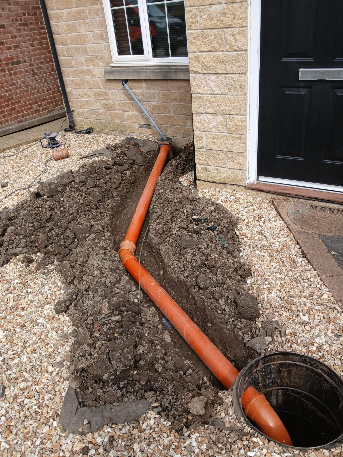 New underground drain run with inspection chamber outside a front door