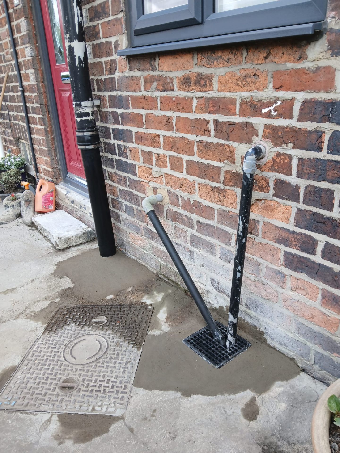 Reinstated concrete around manhole cover with new gully and downpipes