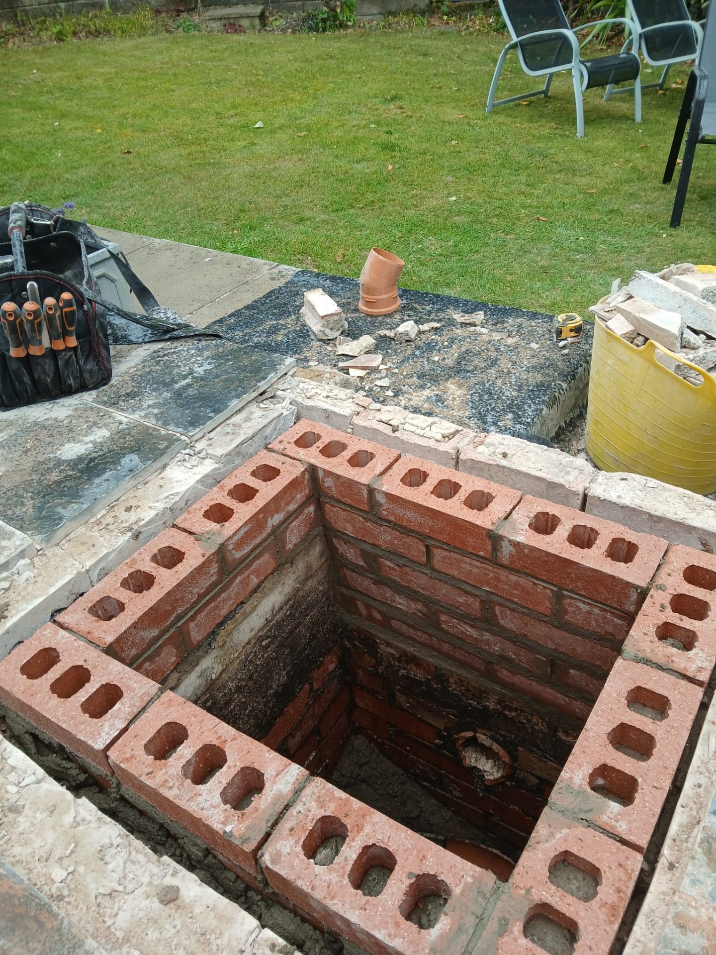 Brick-built inspection chamber under construction in a back garden patio