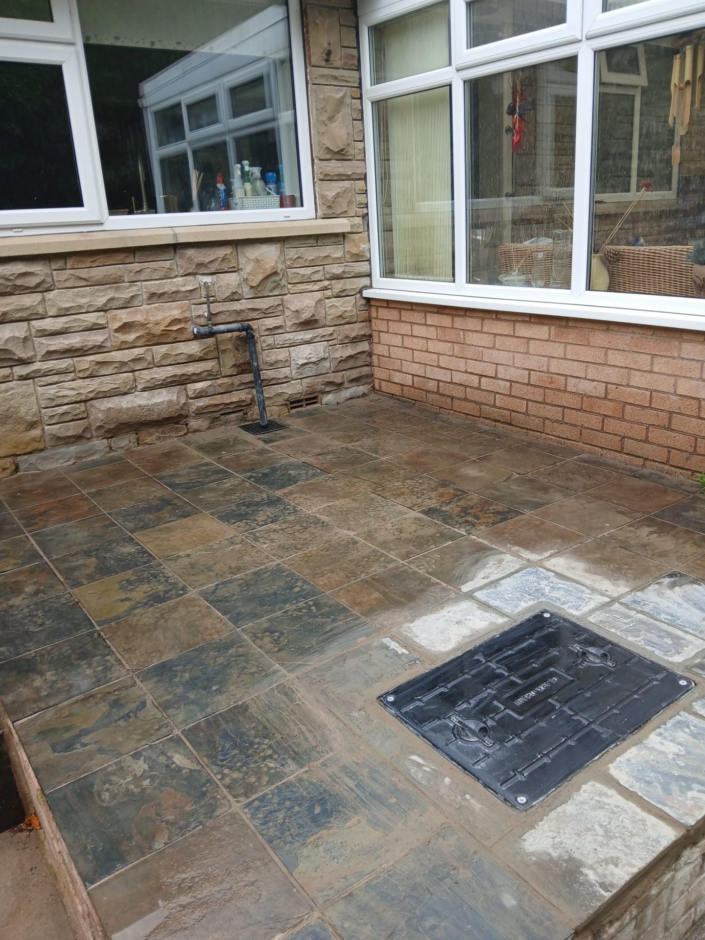 Finished slate patio with neat manhole cover and clean drainage outlet